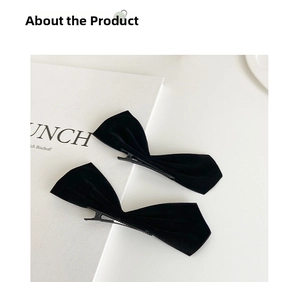Detail of two black velvet bow hair clips with metal duckbill clips on a book