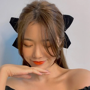 Detail of a chic black velvet bow hair clip worn on a model for a stylish look