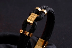 Detail of black braided leather bracelet with gold stainless steel cross magnetic clasp