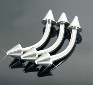 Close-up of three silver stainless steel curved barbells with spike ends for body piercing