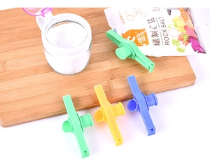 Set of four colorful plastic food sealing clips with pour spouts on a wooden board