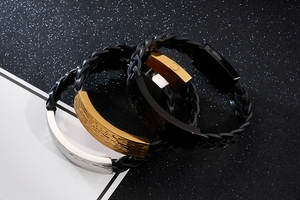 Detail of woven leather bracelets featuring hammered metal plates in silver gold and black