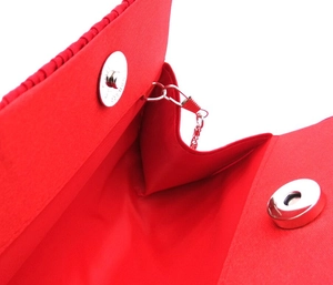 Detail showing the magnetic closure and silver hardware of the red satin evening bag