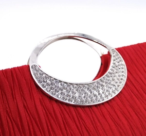 Detail of red pleated evening bag with silver rhinestone-encrusted metal handle