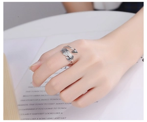 Close-up of retro silver feather and arrow ring on hand with vintage book background