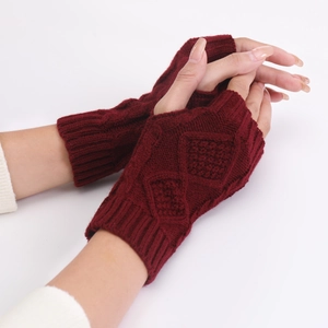 Close-up of deep red cable-knit fingerless gloves with detailed diamond pattern texture