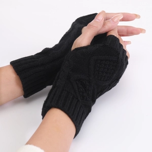 Detail of black cable knit fingerless gloves showing thick texture and thumb hole design