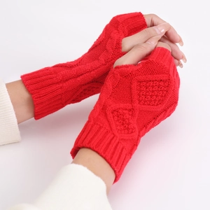 Close-up of red cable-knit fingerless gloves with thumb hole on a soft beige background