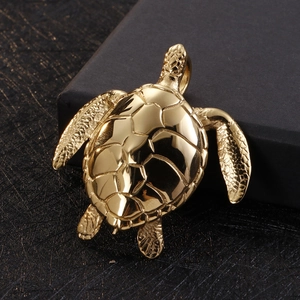Macro shot of a golden sea turtle pendant with detailed shell texture on black background