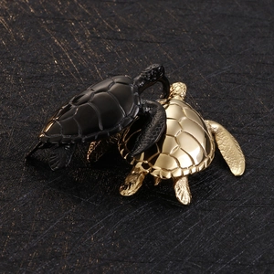 Detailed view of turtle pendants in black and gold finishes with polished metal texture