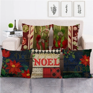Set di cinque fodere per cuscini natalizi in lino con stampe NOEL su divano beige