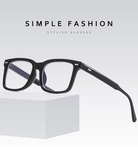 Details einer schwarzen quadratischen Brille mit Silbernieten auf einem weißen Podest