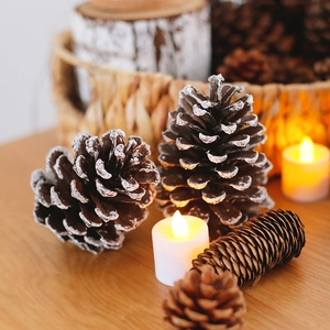 Natural pine cones with snow spray and LED tea light candles for festive Christmas decor