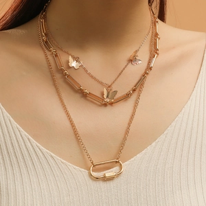 Detail of layered gold hip hop necklace featuring butterfly charms and paperclip chain