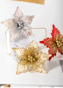 Close-up of glitter fabric Christmas flowers in gold, red, and champagne silver