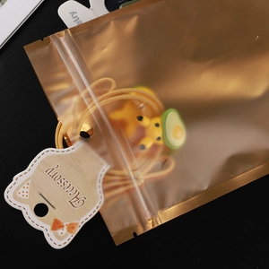 Matte gold aluminum foil seal bag with cartoon yellow hair tie inside for jewelry packaging