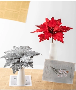 Macro detail of red and silver artificial poinsettia with glitter on a white ceramic vase