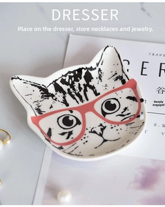 Detail of creative cat ceramic jewelry tray with red glasses design and pearl accents
