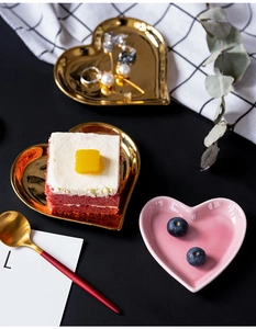 Close-up of heart-shaped ceramic and gold plates with dessert on an elegant table