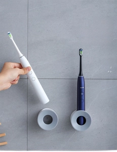 Close-up of wall-mounted gray electric toothbrush holder on dark bathroom tile