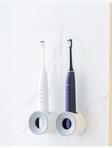 Detail of two wall-mounted electric toothbrush holders with hollow drainage on marble wall