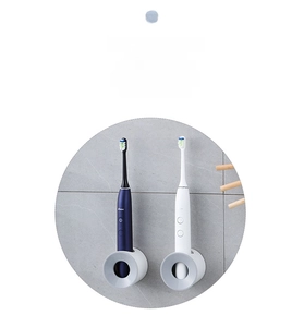 Close-up of wall-mounted electric toothbrush holders in white and blue on tiled wall