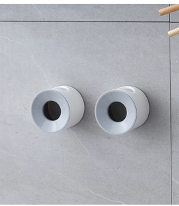 Wall-mounted cylindrical electric toothbrush holder on a grey marble tile bathroom wall