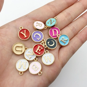 Colorful alloy alphabet charms with gold trim held in hand to show size and detail