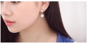 Detailed close-up of a pearl earring with sparkling rhinestones worn on an ear