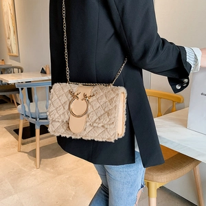 Detail of beige plush crossbody bag featuring gold chain and reindeer horn clasp