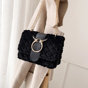 Detail of plush black crossbody bag featuring golden deer head buckle and chain strap
