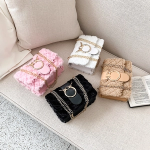 Detail view of four plush crossbody bags in various colors on a beige sofa with gold chains