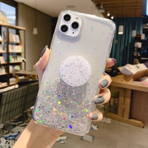 Starry glitter phone case for iPhone with matching grip stand held in a cozy cafe