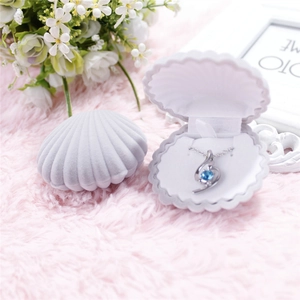 Detailed view of an open shell jewelry box with a blue gemstone necklace on plush fabric