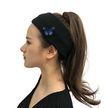 Detail of black knitted headband with a blue butterfly embroidery patch on a female model