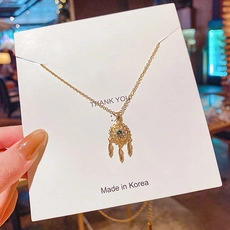 Dettaglio della collana acchiappasogni dorata con pietra verde e ciondoli piuma