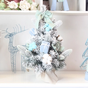 Flocked mini Christmas tree with blue bows and cotton decorations on a burlap base