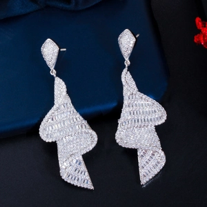 Detailed view of silver geometric spiral drop earrings with micro-set zircons on silk