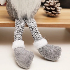 Detail of Christmas gnome plush with sequined knit legs and grey felt on wooden surface
