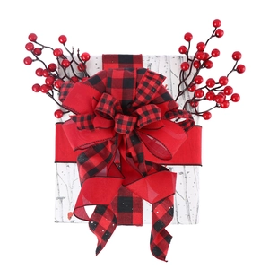 Macro detail of red and black plaid ribbon bow with berries on a white gift box