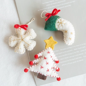 Handmade wool felt Christmas tree ornaments with snowflake and stocking on vintage magazine