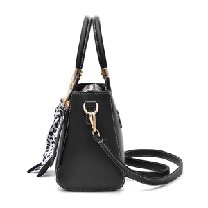 Black leather handbag with leopard scarf and gold hardware on white background