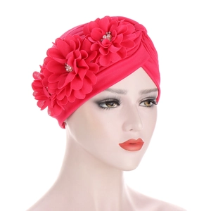 Détail d'un turban rouge pour femme avec trois fleurs 3D et ornements de perles centrales