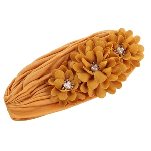 Détail macro du turban plissé jaune avec trois fleurs décoratives ornées de perles