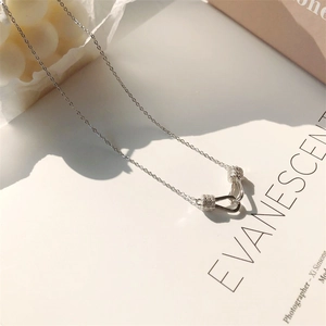 Detailed view of silver U-shaped pendant necklace with cubic zirconia on white background