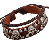 Close-up of vintage brown leather bracelet featuring five bronze skull metal accents