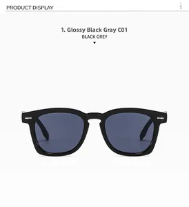 Detailed close-up of glossy black square sunglasses with silver metal rivets and grey lenses