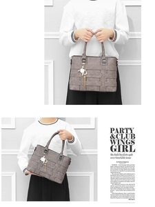 Detail of grey woven leather handbag with stylish metallic tassel and white fur charm