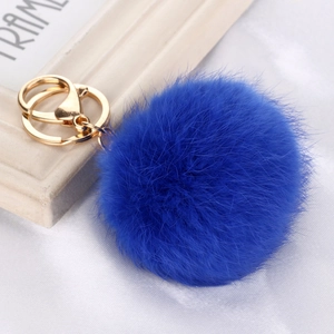 Macro detail of royal blue faux fur pompom keychain with golden metal lobster clasp