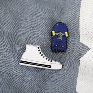 Blue skateboard brooch with slogan and white high-top sneaker enamel pin on denim